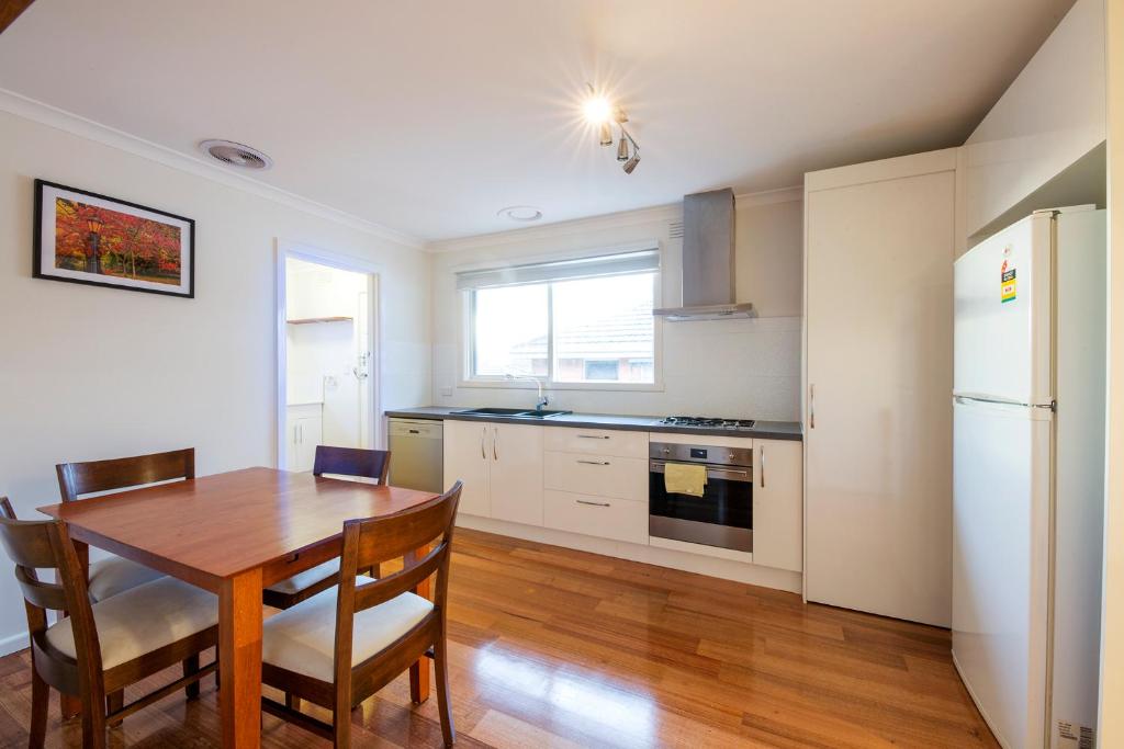 een keuken met een houten tafel en een koelkast bij Rent Melbourne in Melbourne