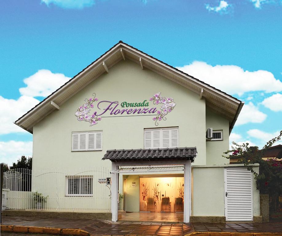 a white building with a sign on the side of it at Pousada Florenza in Bento Gonçalves