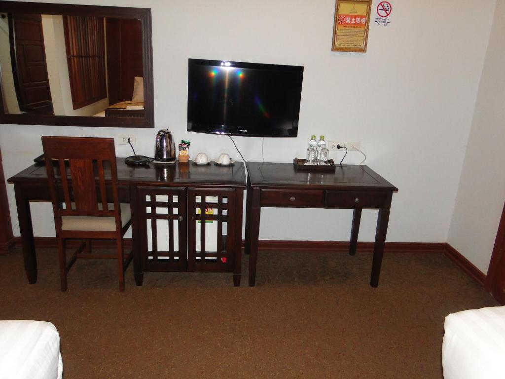 a room with a desk and a television on a wall at Charming Lao Hotel in Ban Chéng