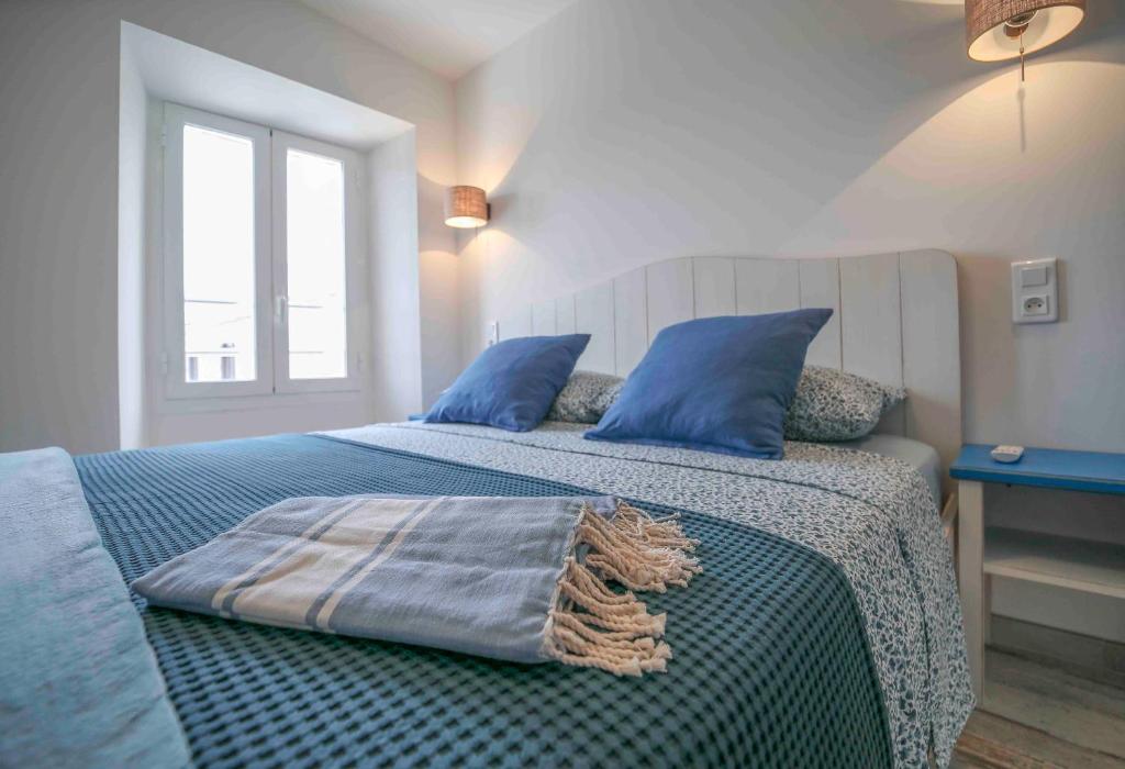 a bed with blue pillows and a blanket on it at Faro della Madonetta in Bonifacio