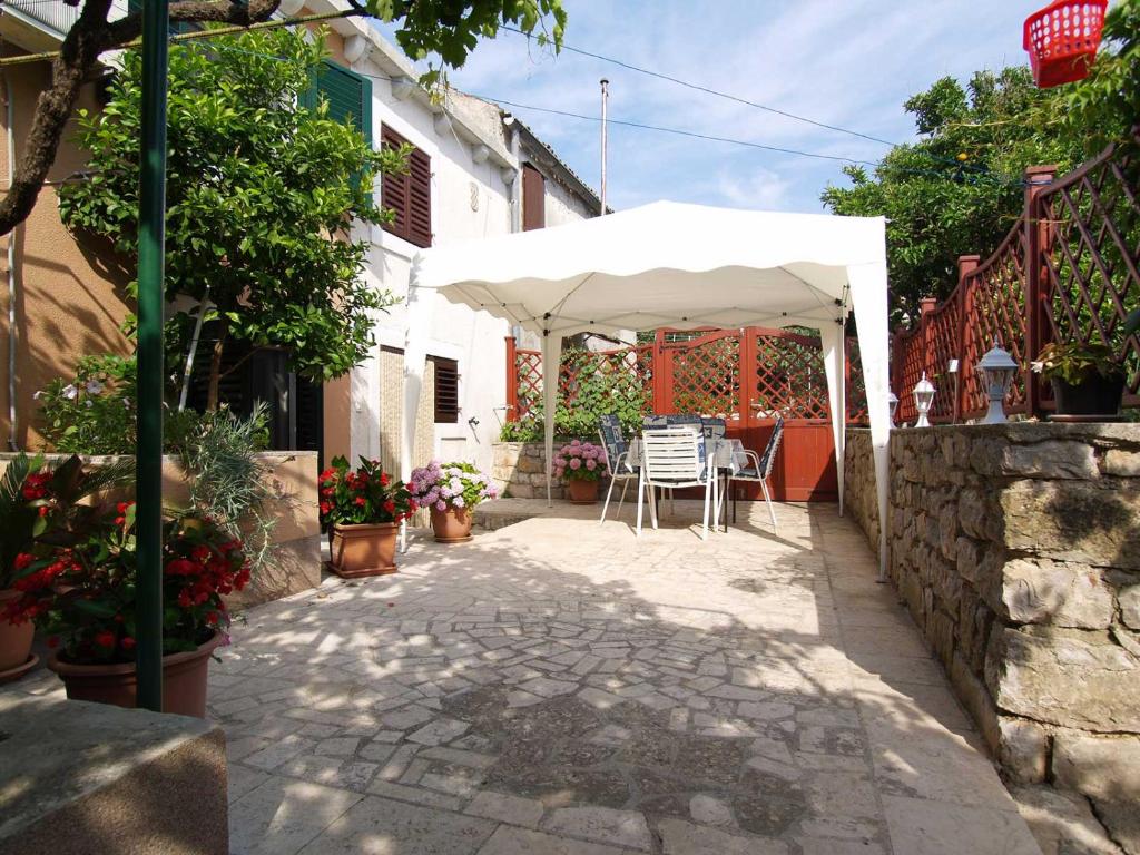 a patio with a white umbrella and a table at Teo in Veli Lošinj