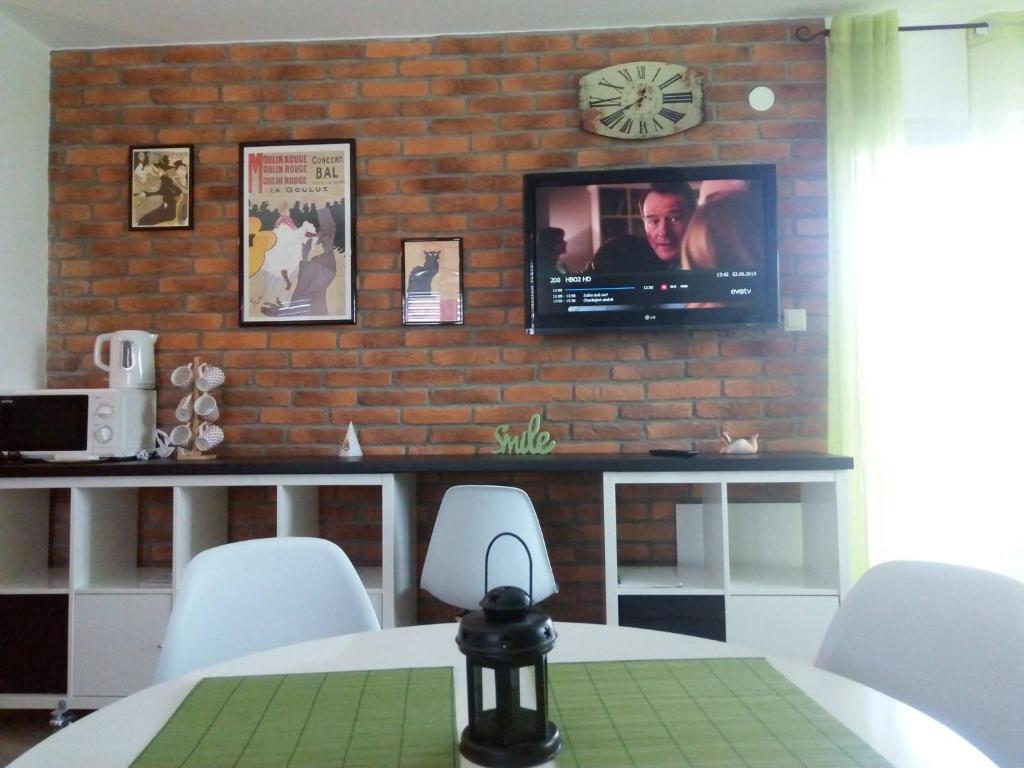 een eetkamer met een tv aan een bakstenen muur bij Studio Relax Punat in Punat