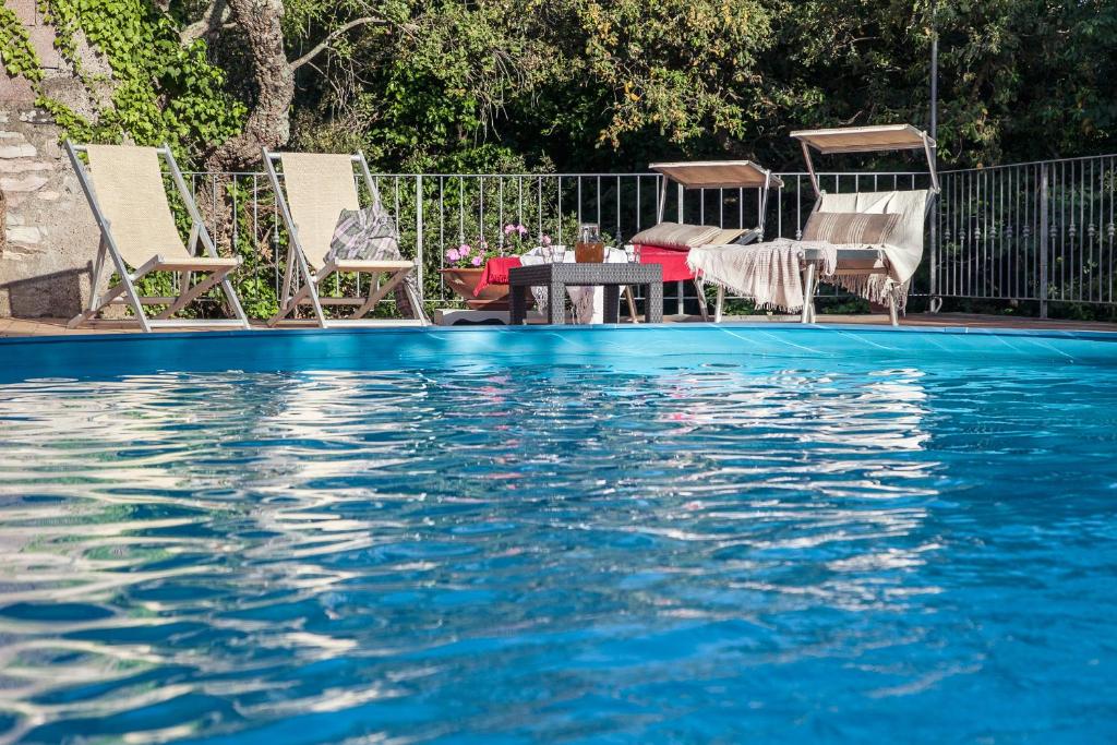 a swimming pool with chairs and a table next to a tableministic at Locanda degli Alberi in Sassetta