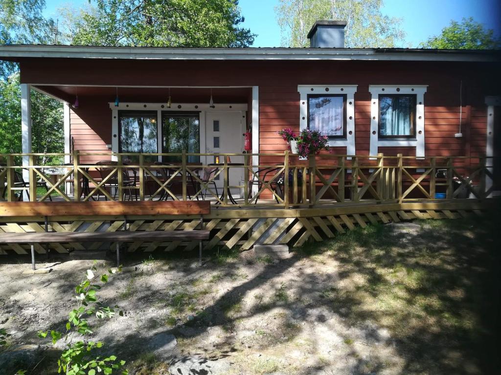 una pequeña casa con una gran terraza de madera en Pirttiniemen Lomakylä, en Muurasjärvi