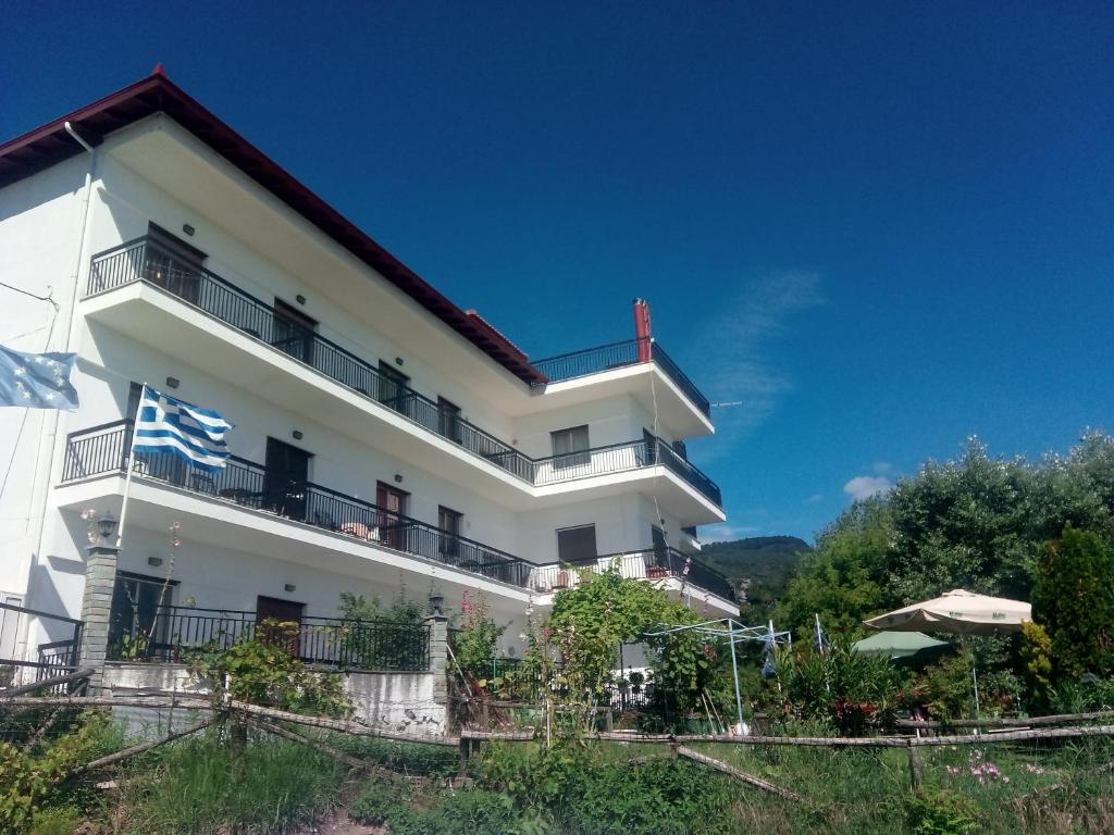 a white building with balconies and a blue sky at Pension Olympus in Litochoro