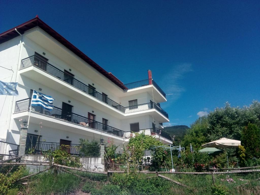 un edificio blanco con balcones y un cielo azul en Pension Olympus, en Litóchoron