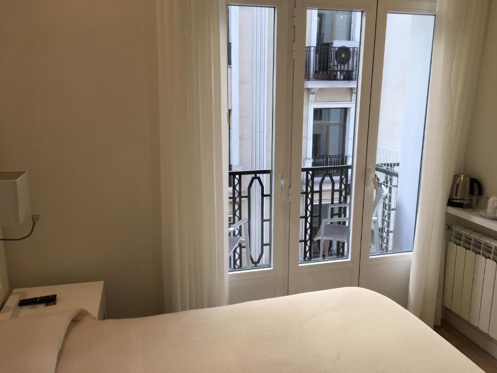 a bedroom with a bed and a window with a balcony at Rincón de Gran Vía in Madrid