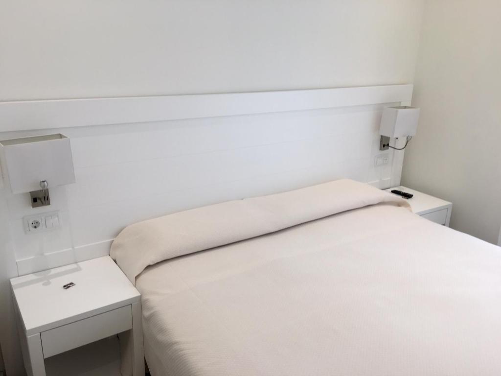 a white bedroom with two tables and a bed at Rincón de Gran Vía in Madrid