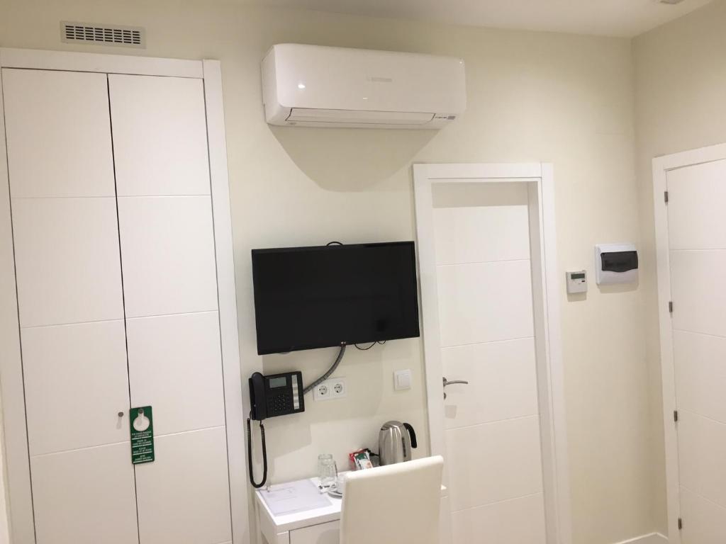 a white bathroom with a television and a phone at Rincón de Gran Vía in Madrid