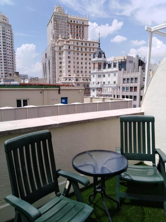 a patio with two chairs and a table on a roof at Rincón de Gran Vía in Madrid