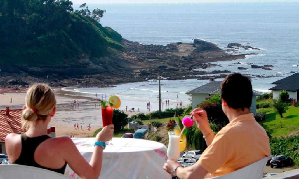 a group of people sitting at a table looking at the beach at Hotel El Refugio 3 estrellas in Cóbreces