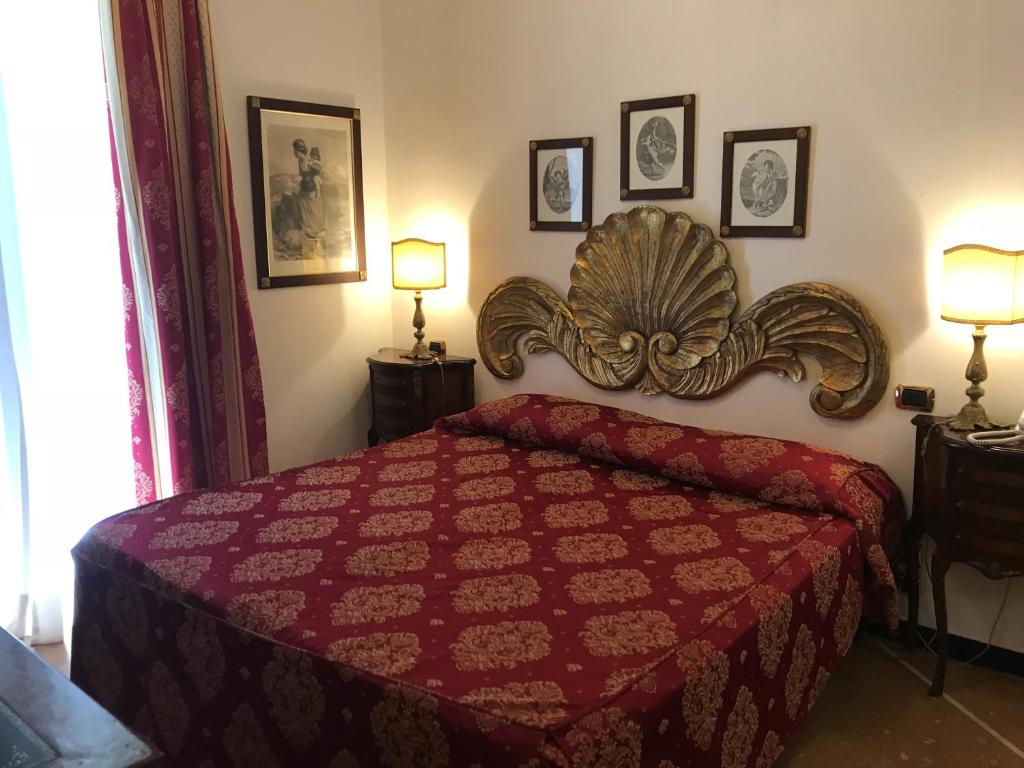 a bedroom with a red bed and two lamps at Hotel Villa Luisa in Rapallo