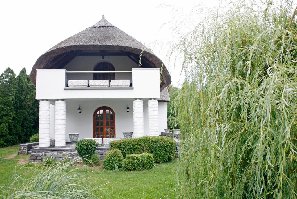 una pequeña casa blanca con techo de paja en The Pearl of Balaton, en Szigliget