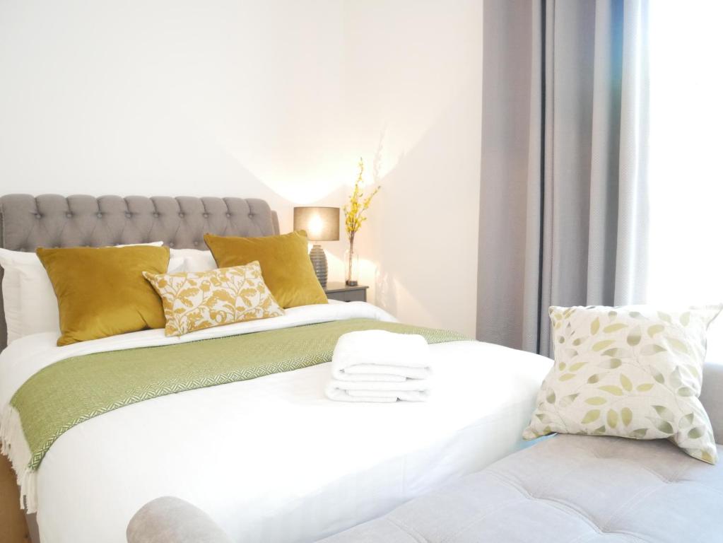 a bedroom with a white bed with yellow pillows at The Gill Gardens Barn - Private Hot Tub Ulverston - Lake District in Ulverston