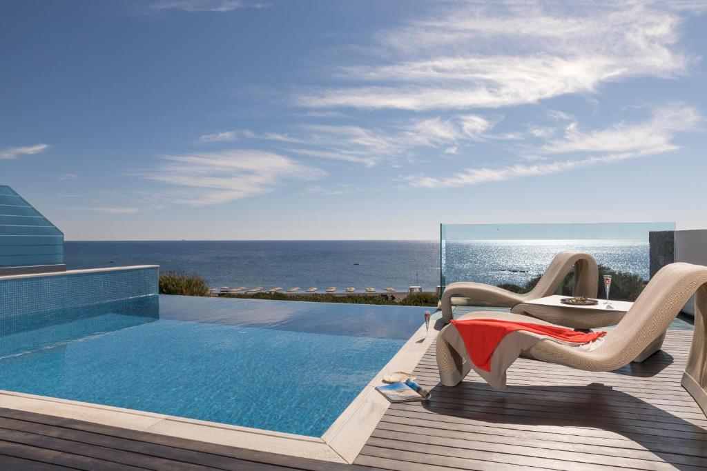 a pool with a table and a chair next to the ocean at Boutique 5 Hotel & Spa - Adults Only in Kiotari