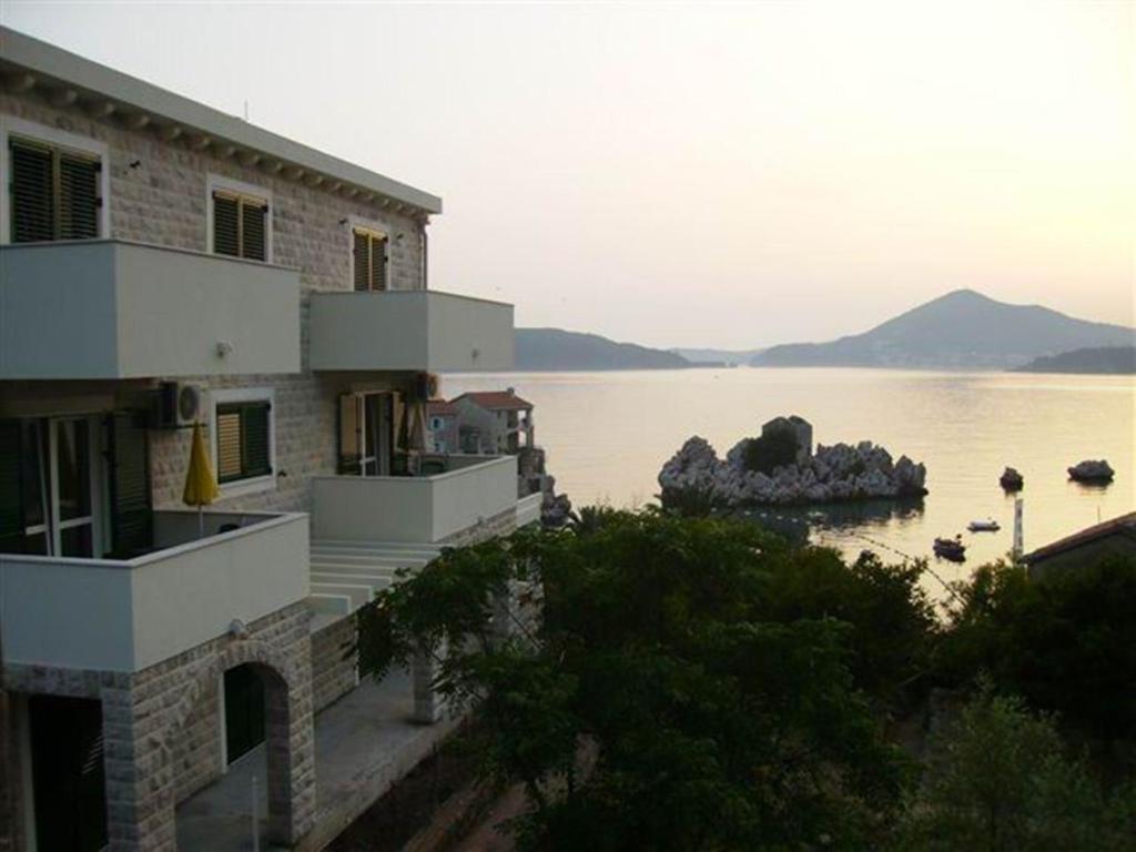 a building next to a large body of water at Guest House Villa Pastrovka in Sveti Stefan