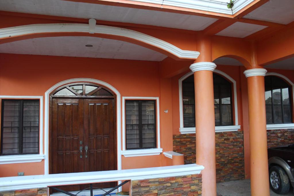 an orange house with a wooden door and two columns at Touristlink Homestay in Donsol