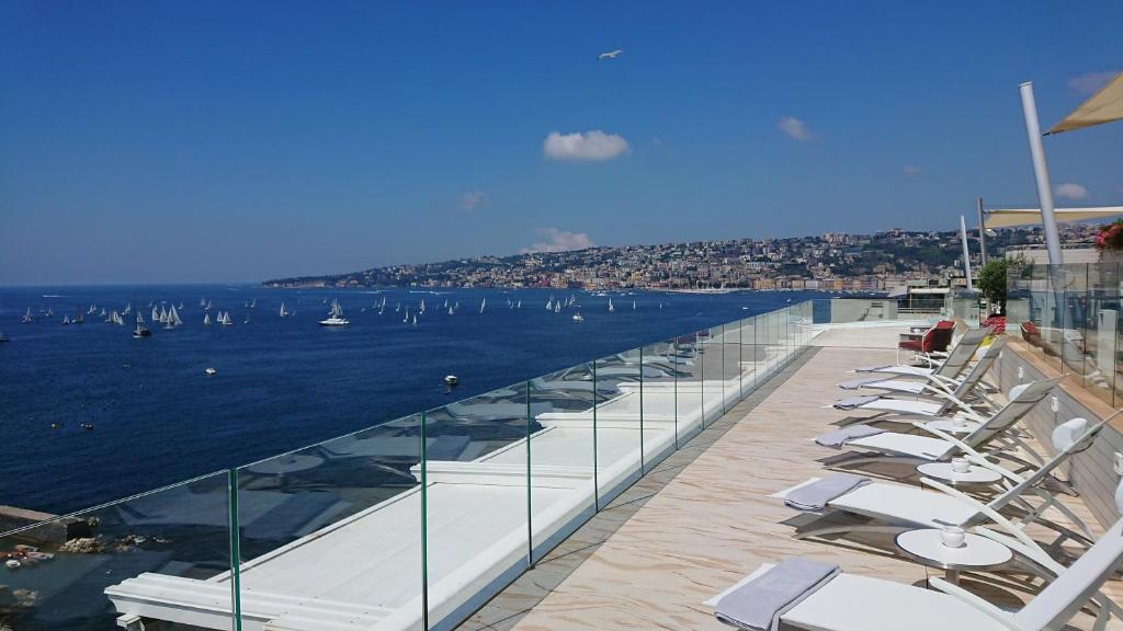 una fila di sedie a sdraio e l'acqua con le barche di Grand Hotel Vesuvio a Napoli