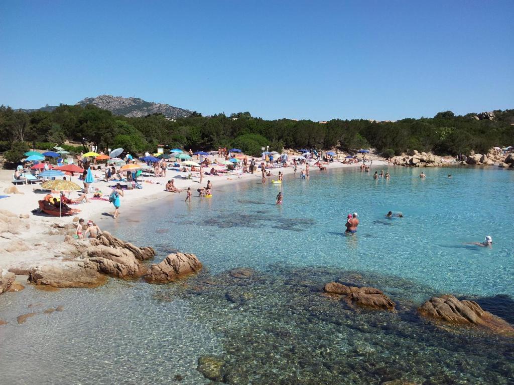 un grupo de personas en una playa en el agua en Residenza Capriccioli en Porto Cervo