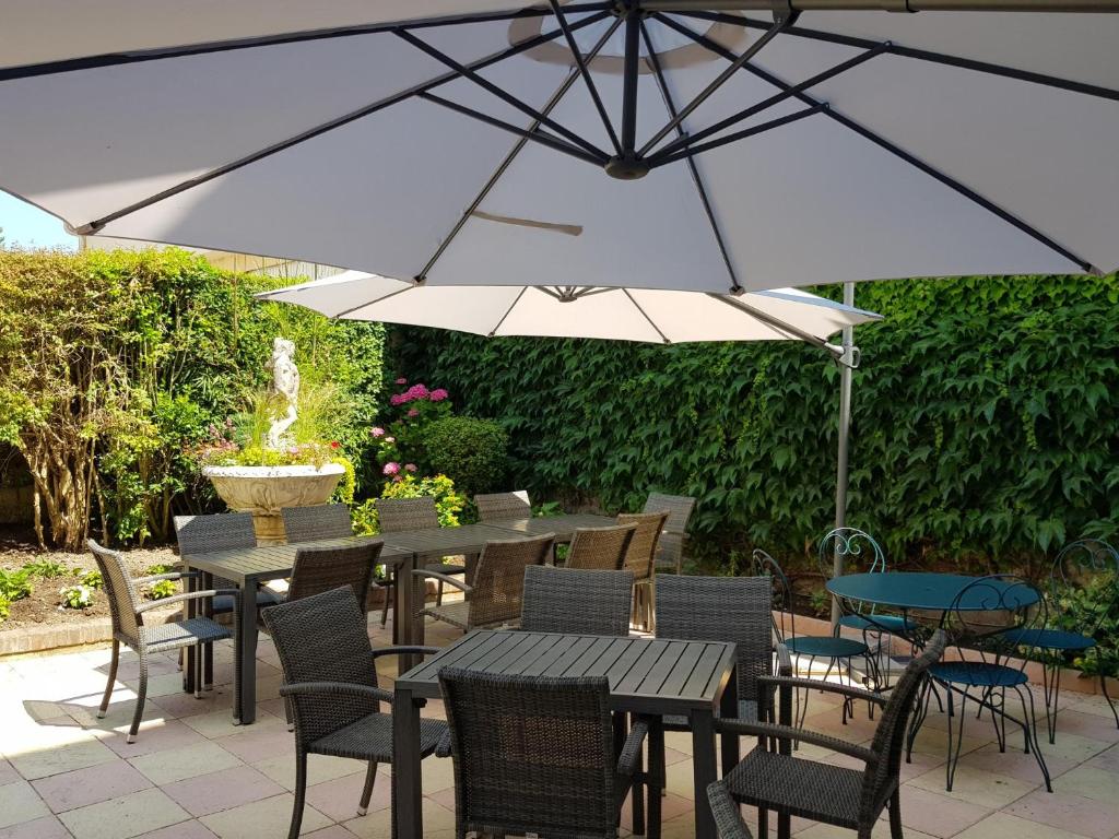 une terrasse avec des tables et des chaises sous un parasol dans l'établissement Come Inn, à Neufchâtel-en-Bray