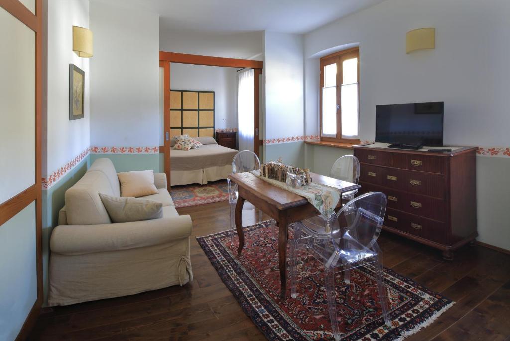un soggiorno con divano, tavolo e TV di Locanda Orologio a Cormòns