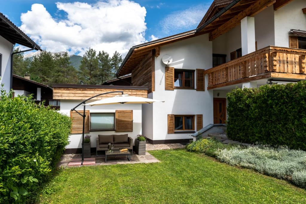 a house with a patio and a lawn at Chalet im Rad - Wanderparadis Tiroler Zugspitze Arena in Ehrwald