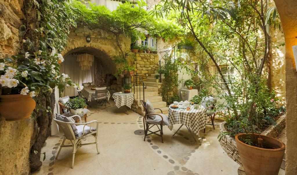 an outdoor patio with tables and chairs and plants at La Cordière in Lourmarin