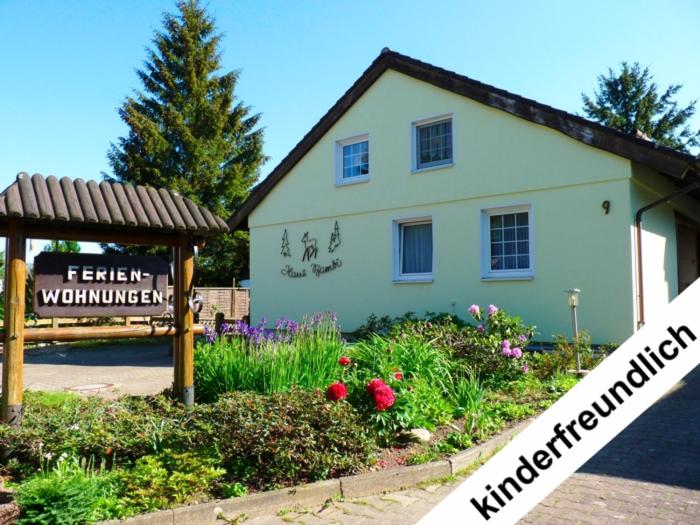 une maison blanche avec un panneau en face d'un jardin dans l'établissement Haus Bambi, à Schulenberg im Oberharz