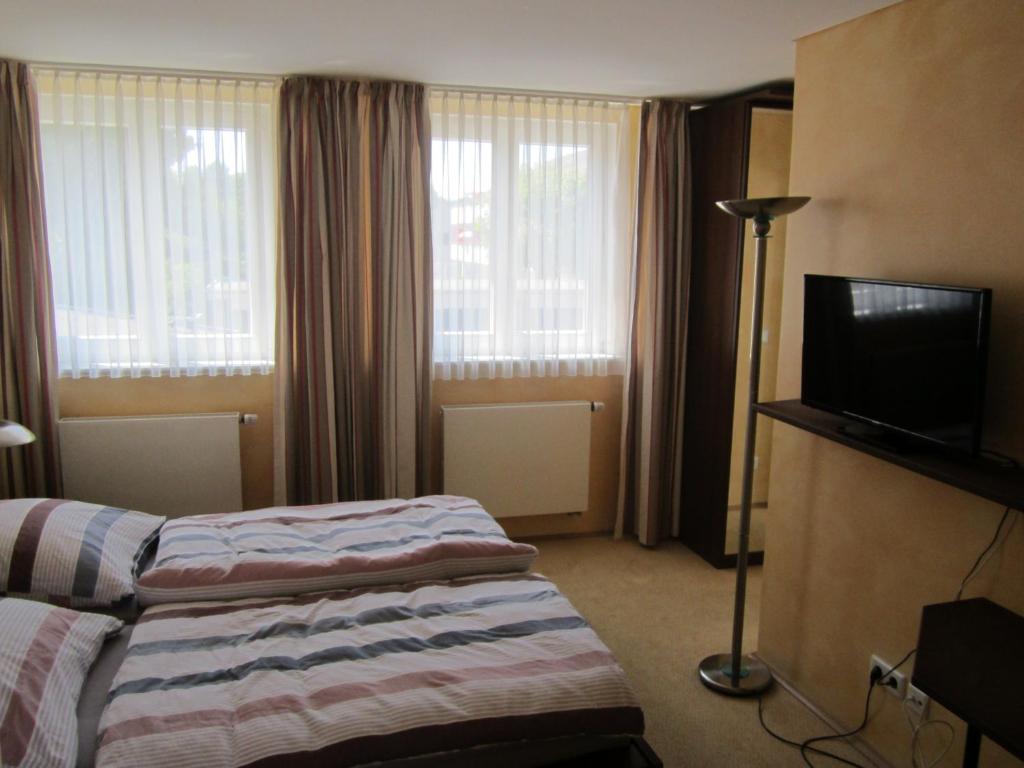 ラーティンゲンにあるDie Kroneのベッド1台、薄型テレビが備わるホテルルームです。