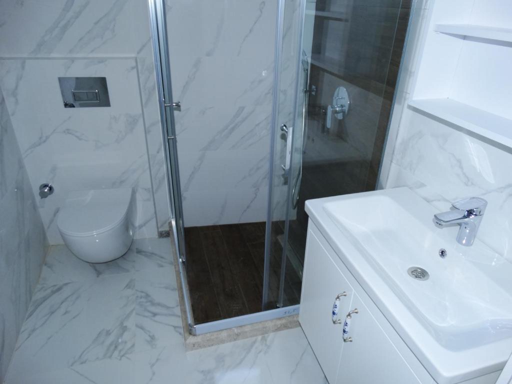 een witte badkamer met een douche en een wastafel bij Çeşme Kale Taş Apart in Çeşme