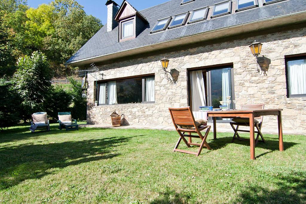 einen Tisch und Stühle vor einem Steinhaus in der Unterkunft Casa Lola Pirene in Vielha e Mijaran