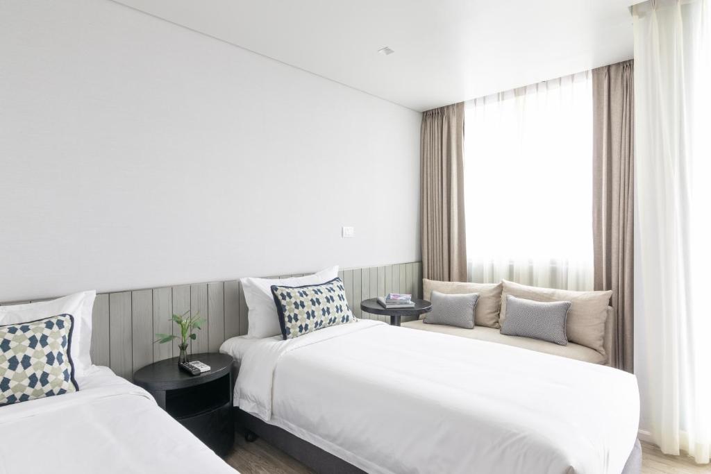 A bright room with two beds and a window-side sofa.