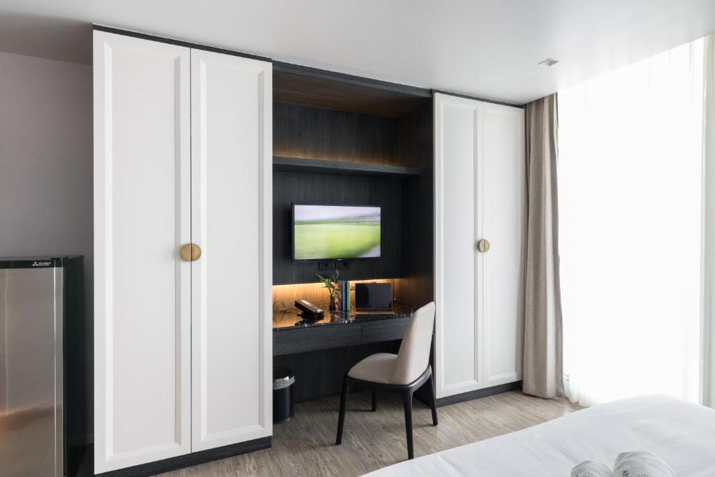 A bedroom wall with a built-in desk, television, wardrobes, and mini-fridge.