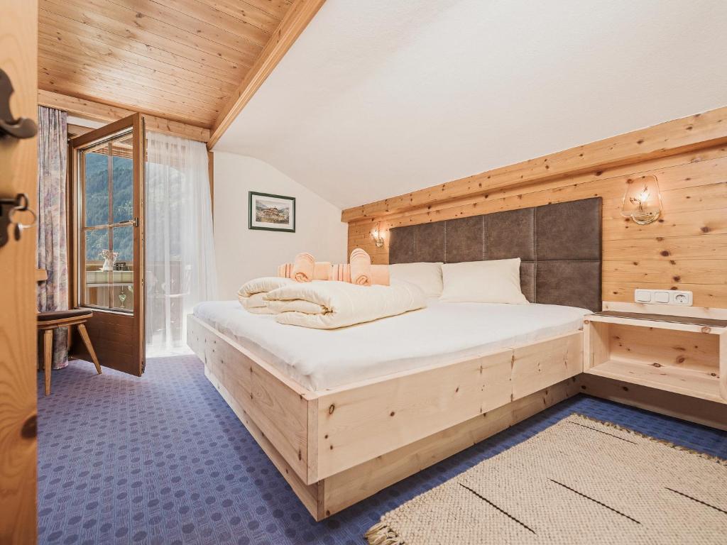 1 dormitorio con 1 cama grande en una habitación con paredes de madera en Ferienwohnungen Fichtenheim, en Mayrhofen