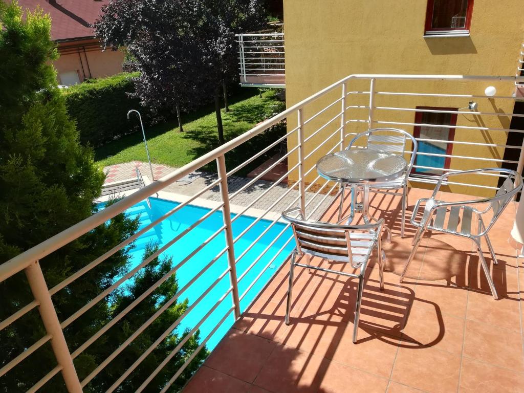 balcón con mesa y sillas junto a la piscina en Janó Apartman, en Siófok