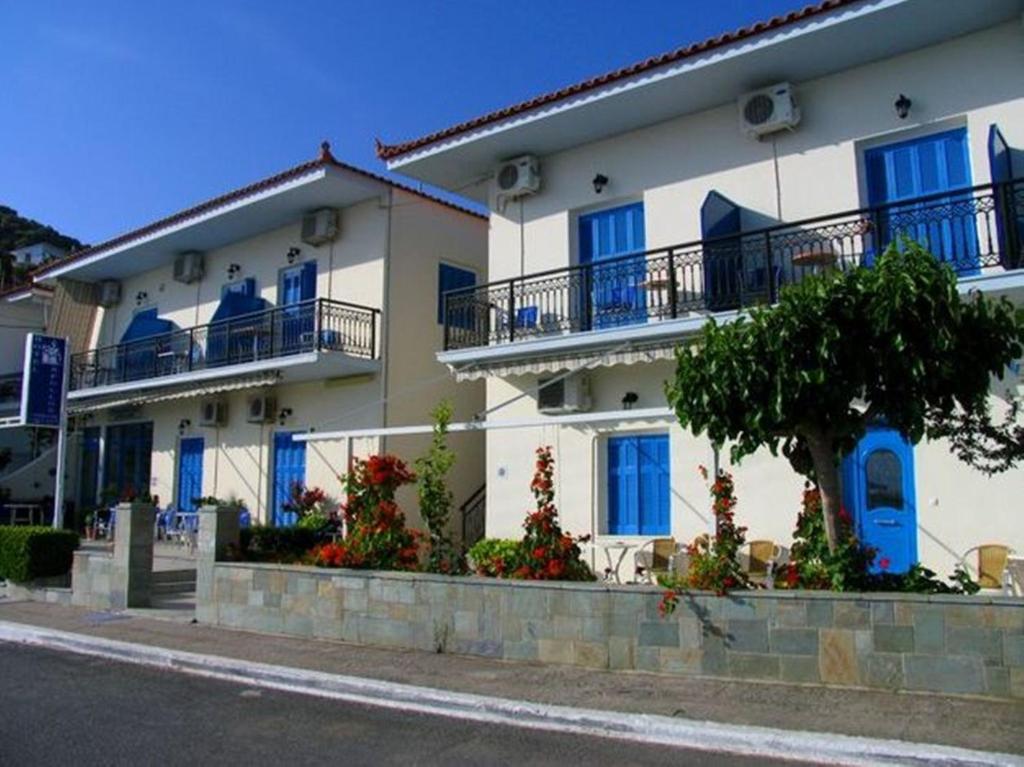un gran edificio blanco con ventanas y balcones azules en Apollon Hotel, en Tyros