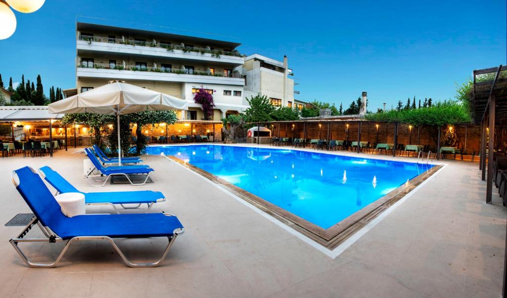 a swimming pool with blue lounge chairs and an umbrella at Miramare in Eretria