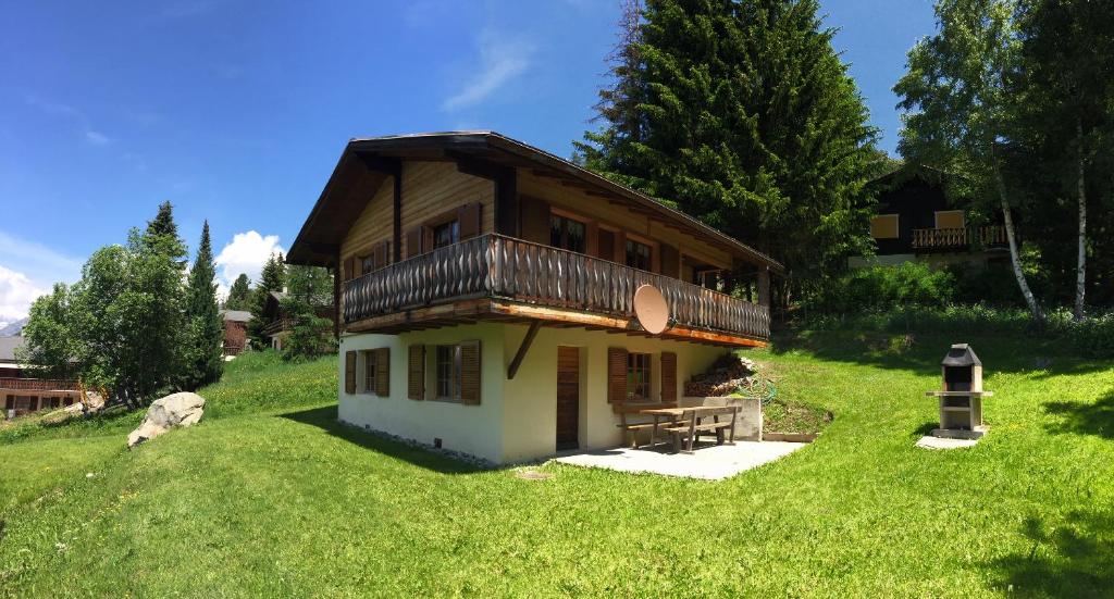 a small house with a balcony on a green field at Chalet Gärlich in Bürchen