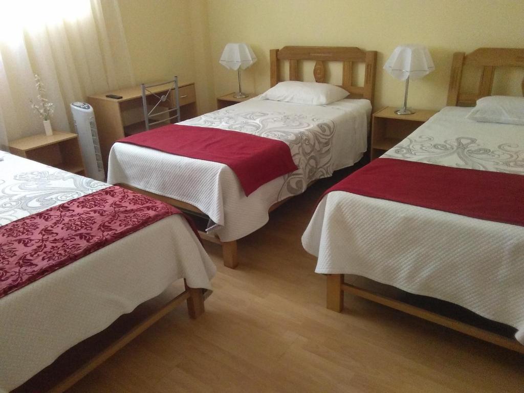 a hotel room with two beds with red and white sheets at Apart & Hostal ManuAlé in Tacna