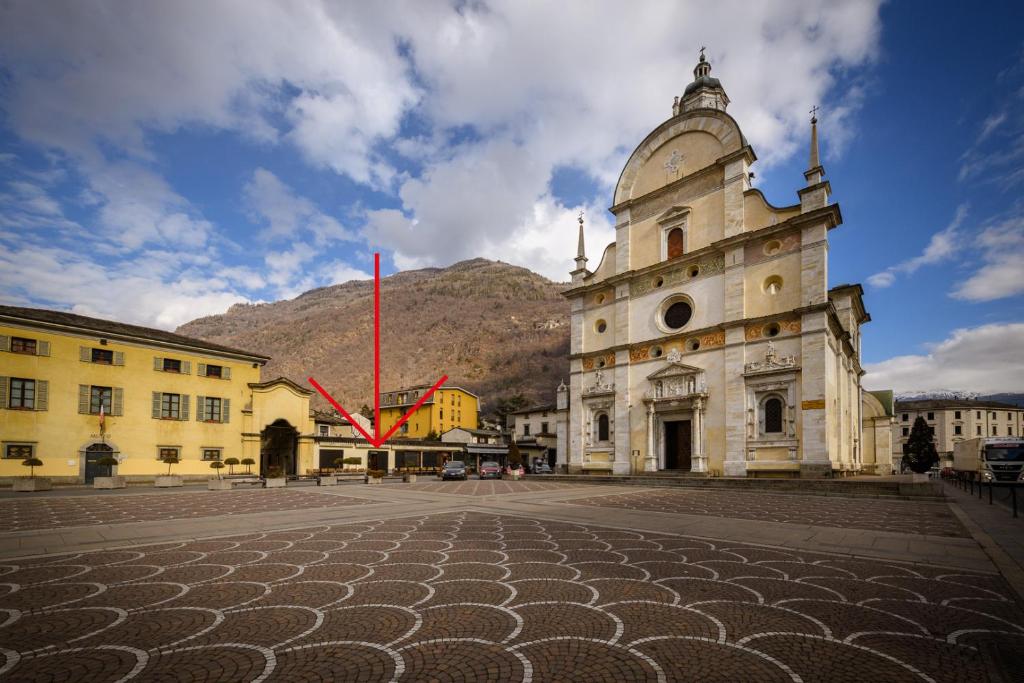 un bâtiment avec une tour avec une montagne en arrière-plan dans l'établissement Casa Nonna Pia, à Tirano