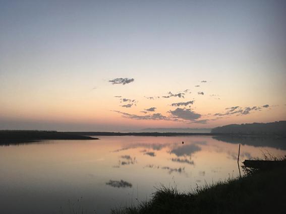 una gran masa de agua con una puesta de sol en el fondo en Arty en Louannec