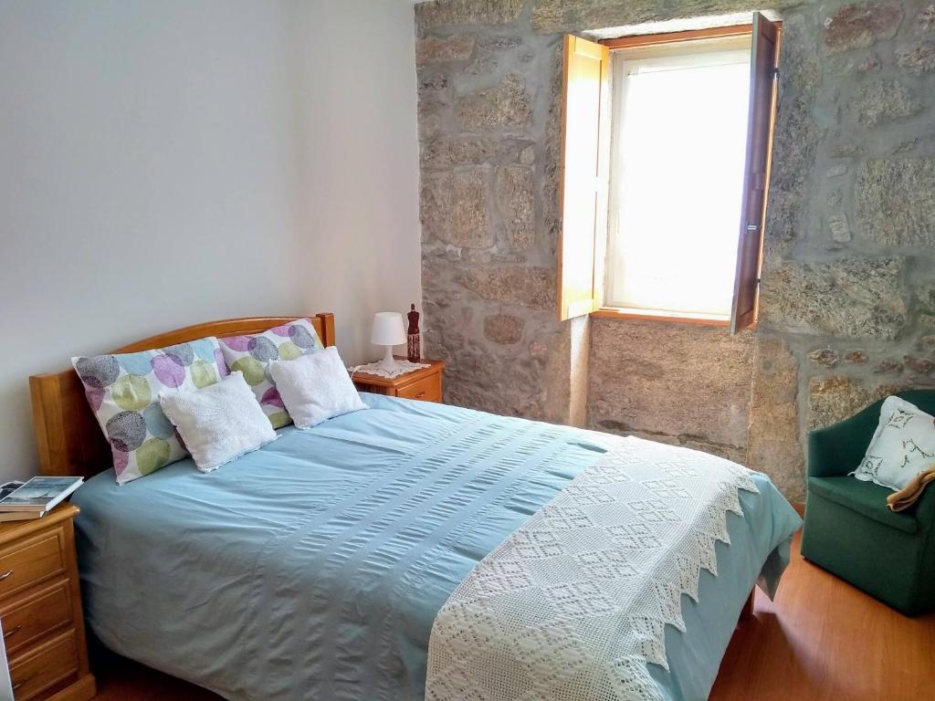 ein Schlafzimmer mit einem Bett, einem Fenster und einem Stuhl in der Unterkunft Casa do Pinheiro Manso in Valença