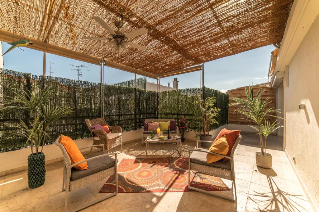 eine Terrasse mit Stühlen, einem Tisch und Fenstern in der Unterkunft Le Berlioz in Nizza