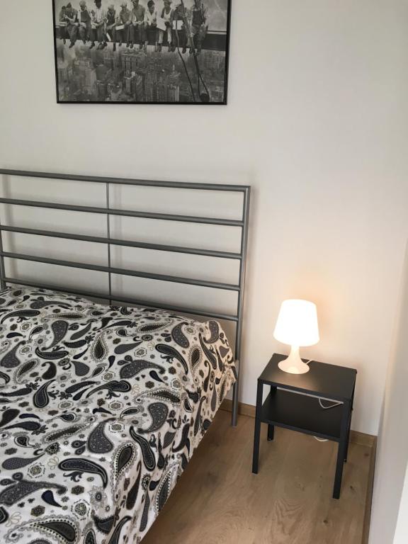 ein Schlafzimmer mit einem Bett und einem Tisch mit einer Lampe in der Unterkunft Apartament Praga in Warschau