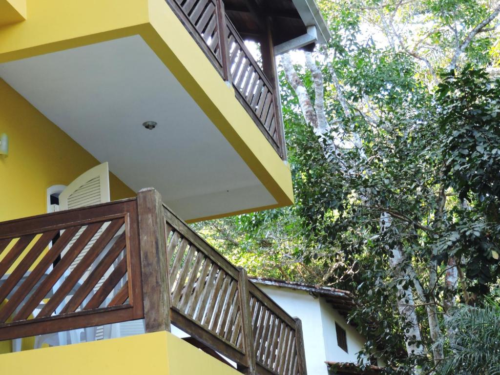 Casa amarilla con árboles y balcones de madera en Pousada do Horto, en Trindade