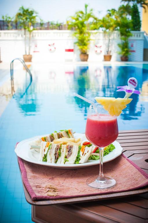 A staged poolside presentation of sandwiches and a bright cocktail.