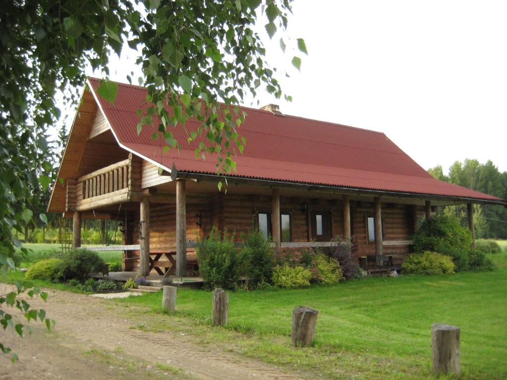 eine große Blockhütte mit rotem Dach in der Unterkunft "Ziedkalni" in Bīriņi