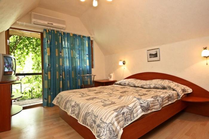 a bedroom with a bed and a television and a window at Santa-Fe Hotel in Koktebel