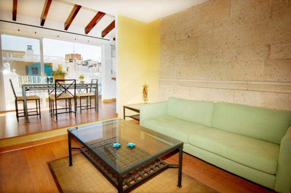 - un salon avec un canapé vert et une table en verre dans l'établissement Atico Amistad, à Séville