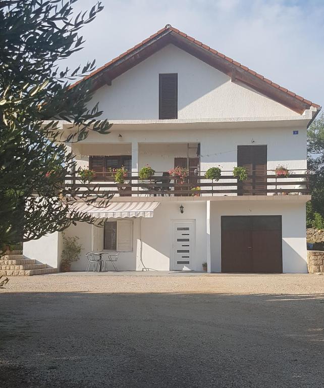 a white house with a balcony and a garage at Apartment Stipe in Maslenica